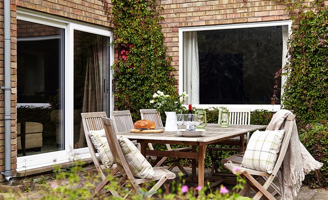 White uPVC patio doors with chrome handle exterior view of wooden garden patio set