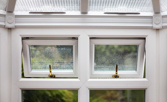 Close up of open top hung UPVC casement windows in conservatory finished with gold window handles from Anglian Home Improvements