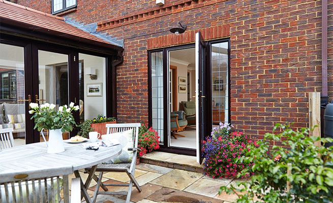 Dark woodgrain uPVC back door with leaded glass side panels open onto the garden patio