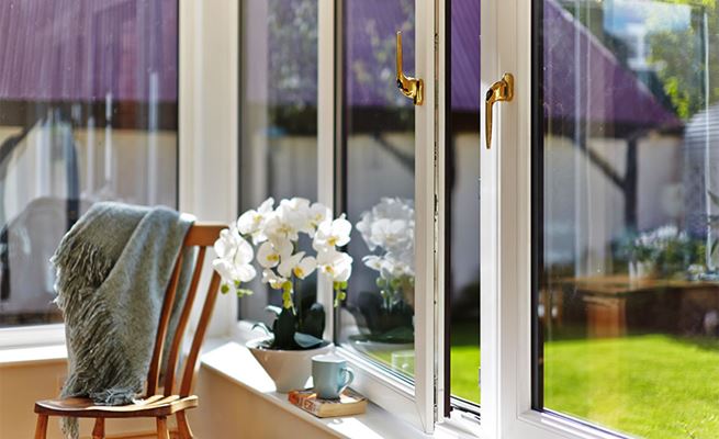 Close up of White UPVC tilt and turn windows opening with a turn finished with gold window handles from Anglian Home Improvements