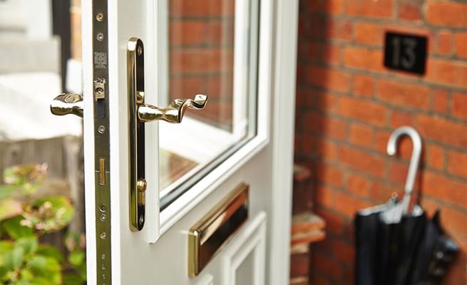 Close up of white wooden front door with gold handle and letterplate from the Anglian wooden front doors range