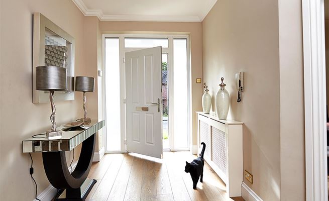 Entrance hall view of open white composite front door in traditional style with chrome handle and letterplate from the Anglian composite doors range