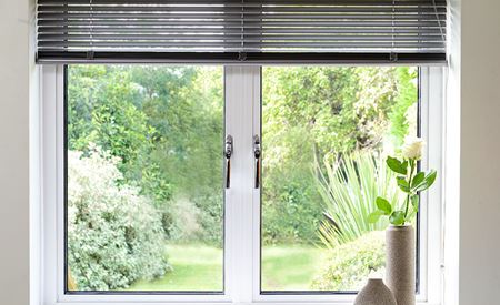 Aluminium double glazed casement window finished in White with chrome handles and blind from Anglian Home Improvements