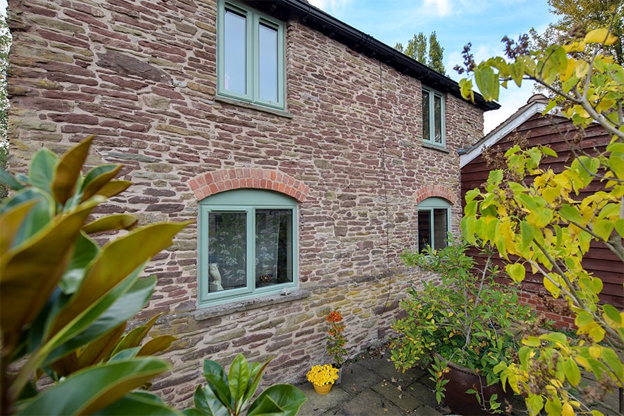 Shaped uPVC casement windows in sage green