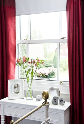 Close up of white wooden sash window interior with red curtains from the Anglian sash window range